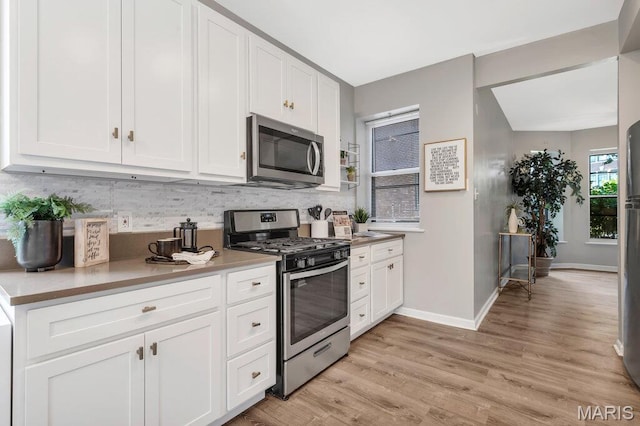 5858 Nina Pl # 1W, Saint Louis, MO 63112 - kitchen with stainless steel appliances, backsplash, white cabinets, and light wood finished floors