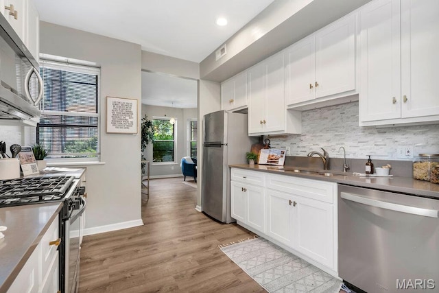 5858 Nina Pl # 1W, Saint Louis, MO 63112 - kitchen featuring appliances with stainless steel finishes, tasteful backsplash, light wood-style flooring, white cabinetry, and recessed lighting