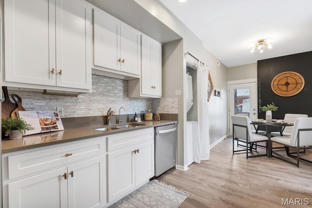 5858 Nina Pl # 1W, Saint Louis, MO 63112 - kitchen with stainless steel dishwasher, backsplash, white cabinetry, light wood-style flooring, and dark countertops