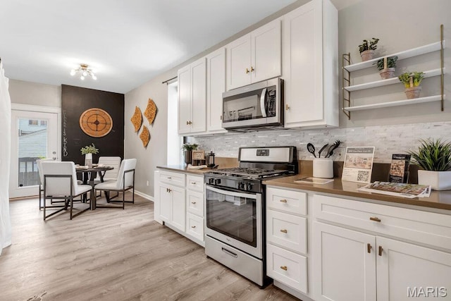 5858 Nina Pl # 1W, Saint Louis, MO 63112 - kitchen featuring stainless steel appliances, decorative backsplash, white cabinetry, and light wood finished floors