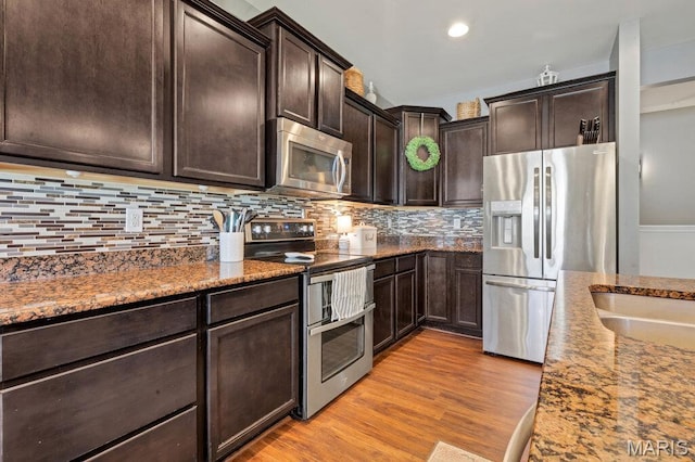 144 Wilmer Valley Dr, Wentzville, MO 63385 - kitchen featuring appliances with stainless steel finishes, dark stone counters, dark brown cabinets, backsplash, and wood finished floors