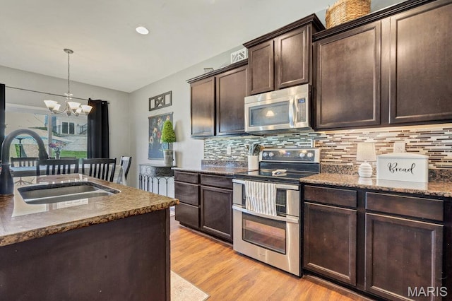 144 Wilmer Valley Dr, Wentzville, MO 63385 - kitchen featuring stainless steel appliances, tasteful backsplash, a chandelier, dark brown cabinetry, and light wood finished floors