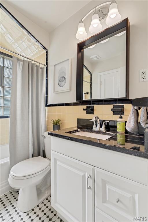 657 Lilac Ave, Webster Groves, MO 63119 - full bathroom with vanity, tile walls, and shower / tub combo with curtain