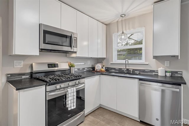 657 Lilac Ave, Webster Groves, MO 63119 - kitchen with stainless steel appliances, dark countertops, white cabinets, and decorative light fixtures