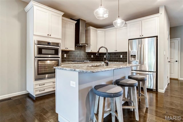 2216 Cournier St, Saint Charles, MO 63301 - kitchen featuring stainless steel appliances, wall chimney range hood, dark wood-type flooring, decorative backsplash, and light stone countertops