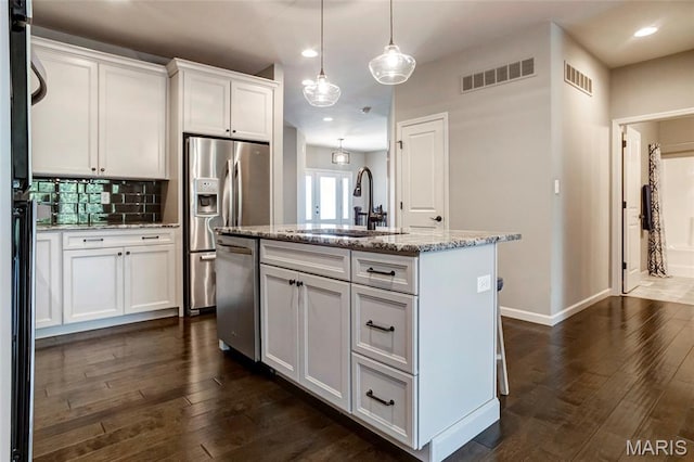 2216 Cournier St, Saint Charles, MO 63301 - kitchen with stainless steel appliances, white cabinetry, recessed lighting, an island with sink, and light stone countertops