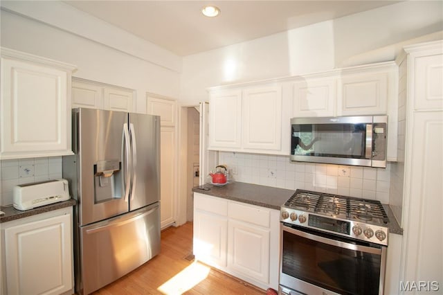 37 Joy Ave, Webster Groves, MO 63119 - kitchen with stainless steel appliances, dark countertops, backsplash, white cabinets, and recessed lighting