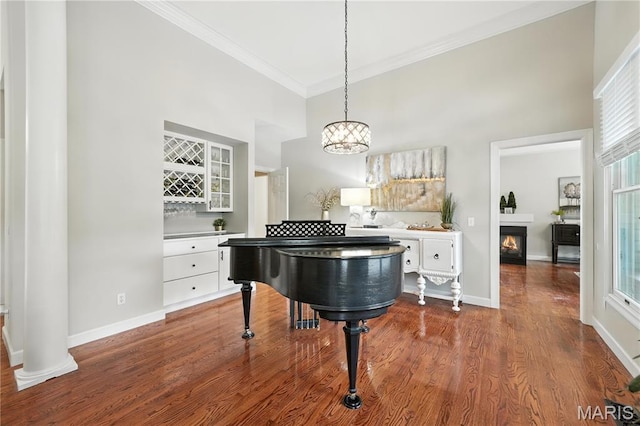 17 Eagles Way Ln, Lake St Louis, MO 63367 - dining space featuring crown molding, a high ceiling, dark wood-style flooring, and a lit fireplace