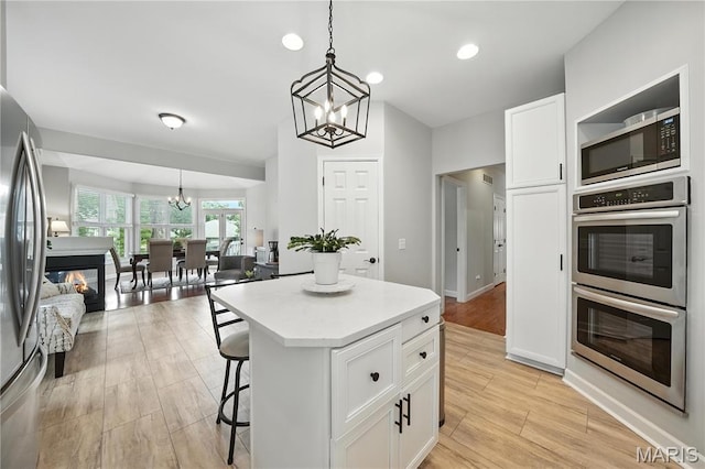 17 Eagles Way Ln, Lake St Louis, MO 63367 - kitchen featuring a chandelier, stainless steel appliances, white cabinetry, a kitchen breakfast bar, and light countertops