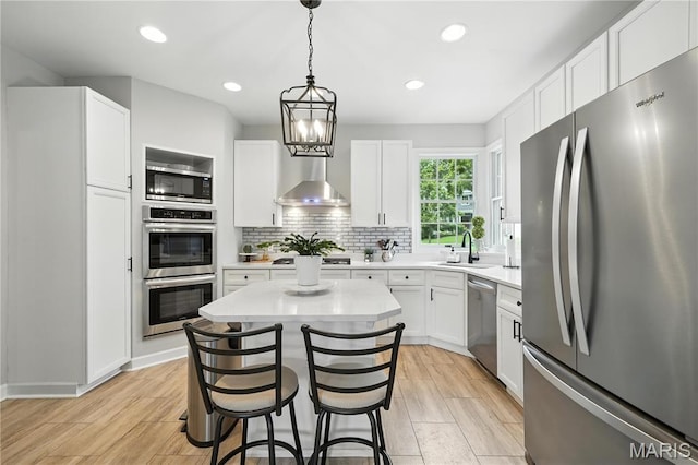 17 Eagles Way Ln, Lake St Louis, MO 63367 - kitchen with stainless steel appliances, wall chimney exhaust hood, light countertops, white cabinets, and a kitchen island
