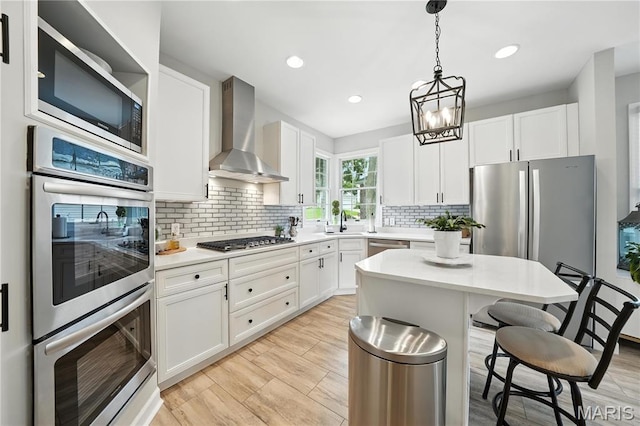 17 Eagles Way Ln, Lake St Louis, MO 63367 - kitchen featuring wall chimney exhaust hood, appliances with stainless steel finishes, a kitchen breakfast bar, white cabinetry, and light countertops