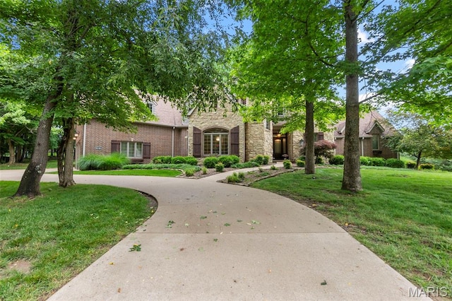 3046 Beaver Creek Cpe, Girardeau, MO 63701 - view of front of house featuring stone siding, a front yard, curved driveway, and brick siding