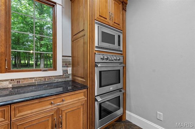 3046 Beaver Creek Cpe, Girardeau, MO 63701 - kitchen featuring stainless steel appliances, brown cabinets, healthy amount of natural light, and dark stone counters