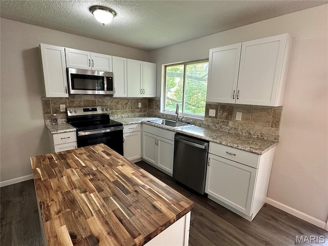 807 Corey Ct, Wentzville, MO 63385 - kitchen featuring appliances with stainless steel finishes, a sink, wood counters, dark wood finished floors, and a textured ceiling