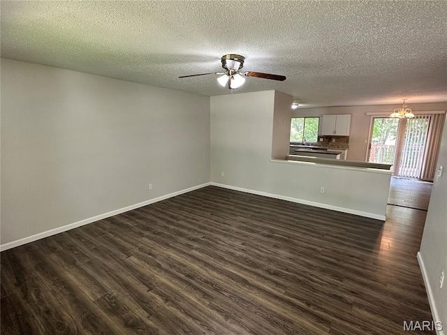 807 Corey Ct, Wentzville, MO 63385 - unfurnished living room featuring a textured ceiling, dark wood-style flooring, baseboards, a ceiling fan, and a chandelier