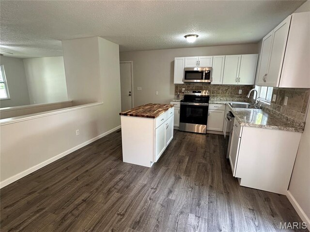 807 Corey Ct, Wentzville, MO 63385 - kitchen featuring stainless steel appliances, butcher block countertops, a textured ceiling, decorative backsplash, and dark wood-style flooring