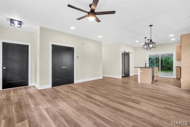 410 Roosevelt, Warrenton, MO 63383 - unfurnished living room with a barn door, a ceiling fan, light wood-style flooring, recessed lighting, and a chandelier