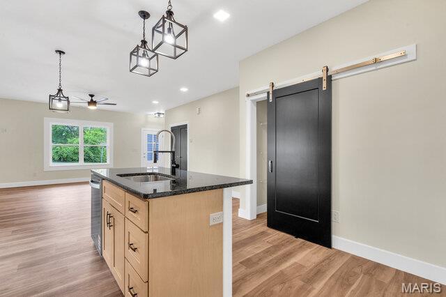 410 Roosevelt, Warrenton, MO 63383 - kitchen featuring light brown cabinetry, stainless steel dishwasher, light wood-style floors, a center island with sink, and decorative light fixtures