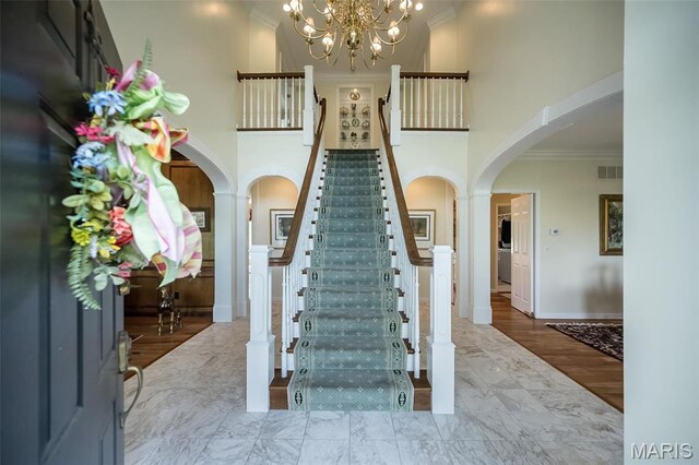 1417 Wheatfield Ln, Saint Albans, MO 63073 - stairway with arched walkways, ornamental molding, a chandelier, and a high ceiling