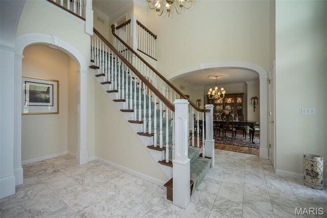 1417 Wheatfield Ln, Saint Albans, MO 63073 - stairway with a chandelier, a towering ceiling, arched walkways, marble finish floors, and crown molding