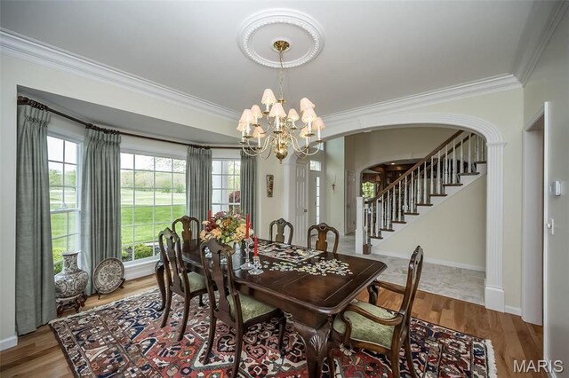 1417 Wheatfield Ln, Saint Albans, MO 63073 - dining area featuring crown molding, arched walkways, a chandelier, stairway, and wood finished floors