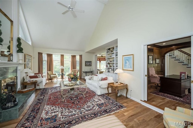 1417 Wheatfield Ln, Saint Albans, MO 63073 - living area with high vaulted ceiling, a glass covered fireplace, wood finished floors, a ceiling fan, and stairs