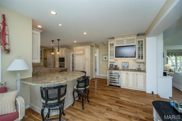 1417 Wheatfield Ln, Saint Albans, MO 63073 - kitchen with wine cooler, a peninsula, a kitchen bar, light wood finished floors, and recessed lighting