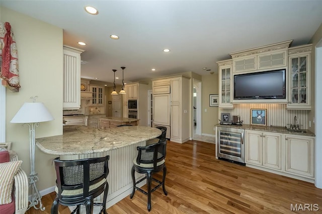 1417 Wheatfield Ln, Saint Albans, MO 63073 - kitchen featuring beverage cooler, cream cabinets, a breakfast bar area, light wood finished floors, and recessed lighting
