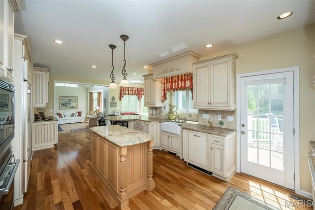 1417 Wheatfield Ln, Saint Albans, MO 63073 - kitchen with open floor plan, light wood finished floors, light stone counters, stainless steel oven, and tasteful backsplash