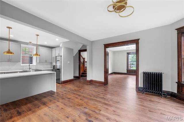 2910 Allen Ave, Saint Louis, MO 63104 - kitchen with radiator heating unit, stainless steel fridge, light countertops, dark wood-type flooring, and healthy amount of natural light