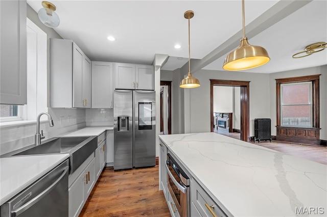 2910 Allen Ave, Saint Louis, MO 63104 - kitchen featuring stainless steel appliances, radiator heating unit, wood finished floors, decorative backsplash, and pendant lighting