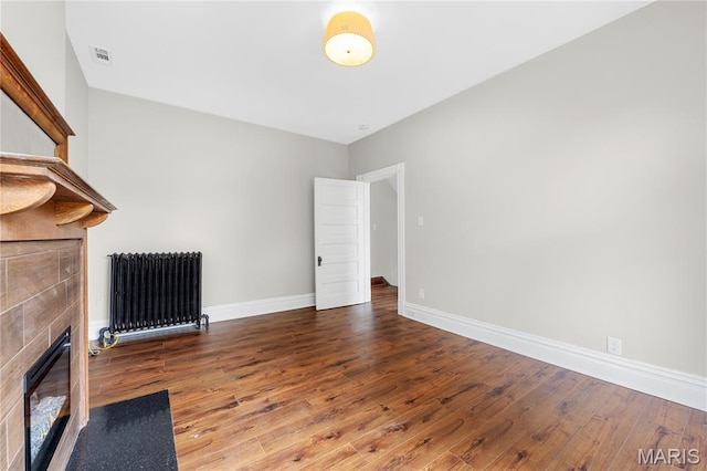 2910 Allen Ave, Saint Louis, MO 63104 - unfurnished living room featuring radiator heating unit, hardwood / wood-style flooring, and a tiled fireplace