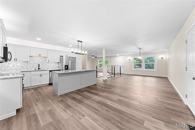 2019 San Pedro Dr, Arnold, MO 63010 - kitchen with appliances with stainless steel finishes, a center island, decorative backsplash, white cabinets, and recessed lighting