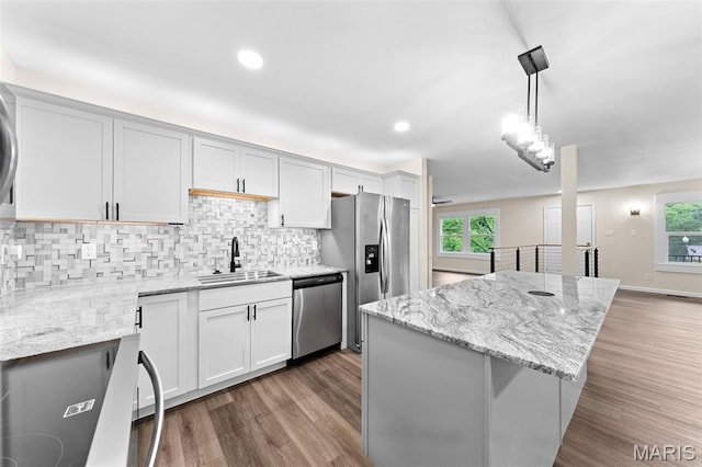 2019 San Pedro Dr, Arnold, MO 63010 - kitchen featuring appliances with stainless steel finishes, backsplash, wood finished floors, a center island, and decorative light fixtures