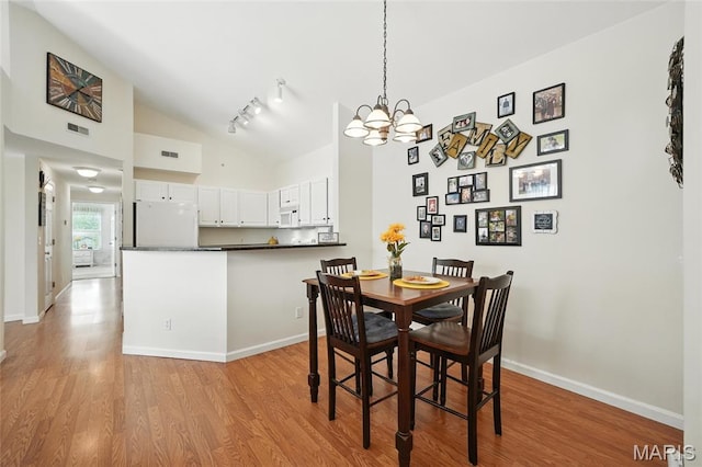 1275 Gardens Circle Drive E, Saint Louis, MO 63125 - dining space with light wood-style flooring, high vaulted ceiling, a chandelier, and rail lighting
