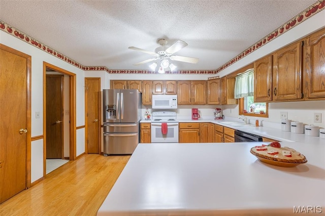 39 Rock Ridge Rd, Wappapello, MO 63966 - kitchen with white appliances, a textured ceiling, light wood-style flooring, light countertops, and brown cabinetry