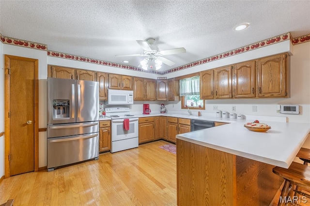 39 Rock Ridge Rd, Wappapello, MO 63966 - kitchen with white appliances, a peninsula, ceiling fan, brown cabinets, and a textured ceiling