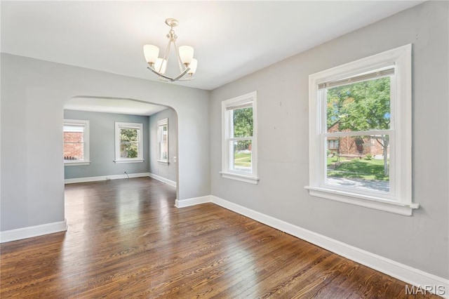 6838 Raymond Ave, Saint Louis, MO 63130 - empty room with a chandelier, arched walkways, and dark wood-type flooring