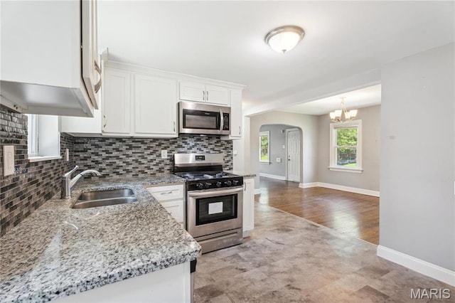 6838 Raymond Ave, Saint Louis, MO 63130 - kitchen featuring stainless steel appliances, a chandelier, tasteful backsplash, and arched walkways