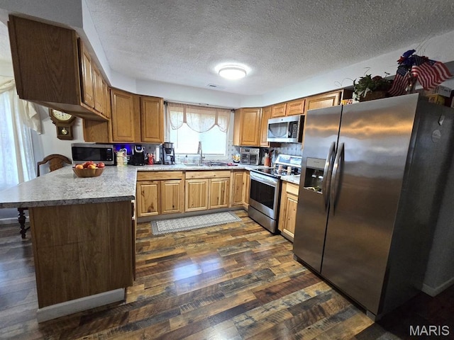 730 N Walnut St, Dexter, MO 63841 - kitchen with appliances with stainless steel finishes, dark wood finished floors, a textured ceiling, a peninsula, and brown cabinetry
