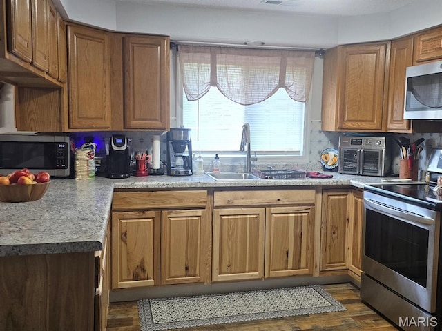 730 N Walnut St, Dexter, MO 63841 - kitchen featuring appliances with stainless steel finishes, dark wood-type flooring, and brown cabinetry