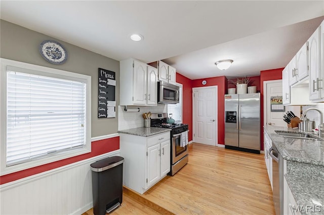 923 N Geyer Rd, Kirkwood, MO 63122 - kitchen with appliances with stainless steel finishes, light wood-style flooring, white cabinets, light stone countertops, and a wainscoted wall