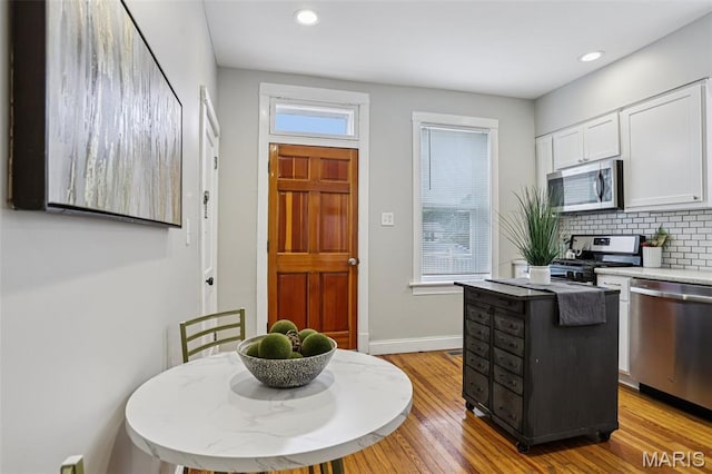 5532 Lansdowne Ave, Saint Louis, MO 63109 - kitchen with appliances with stainless steel finishes, white cabinetry, tasteful backsplash, light wood finished floors, and recessed lighting