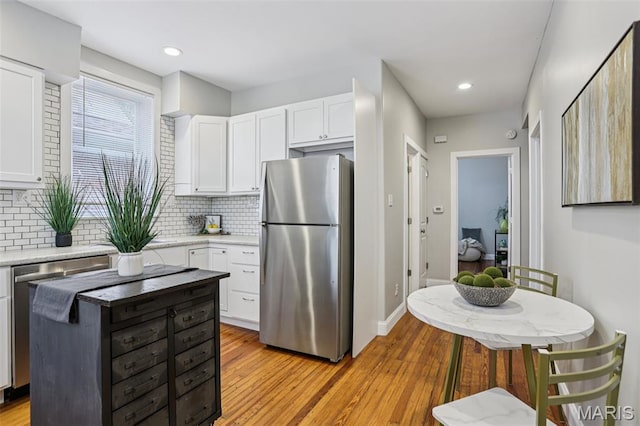 5532 Lansdowne Ave, Saint Louis, MO 63109 - kitchen with stainless steel appliances, backsplash, white cabinets, light wood-style flooring, and recessed lighting
