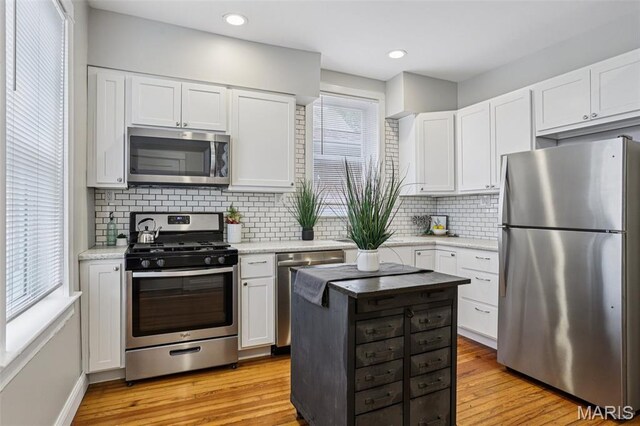 5532 Lansdowne Ave, Saint Louis, MO 63109 - kitchen with stainless steel appliances, white cabinets, tasteful backsplash, light wood-style flooring, and recessed lighting