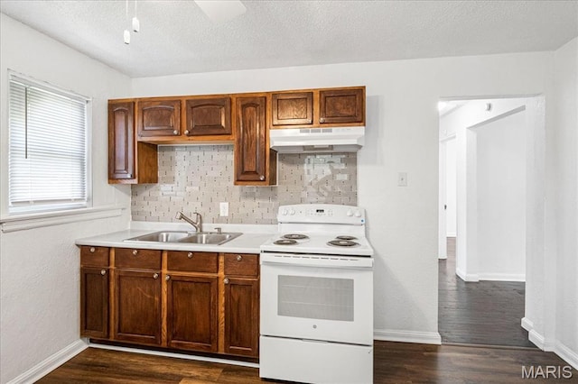8505 Church Bell Ln, Jennings, MO 63136 - kitchen with electric stove, under cabinet range hood, decorative backsplash, light countertops, and dark wood finished floors