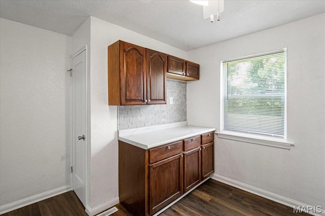 8505 Church Bell Ln, Jennings, MO 63136 - kitchen featuring dark wood-style flooring, light countertops, backsplash, and a textured ceiling