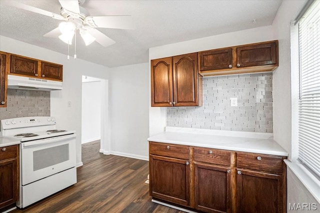 8505 Church Bell Ln, Jennings, MO 63136 - kitchen featuring white range with electric stovetop, under cabinet range hood, backsplash, a ceiling fan, and dark wood-type flooring