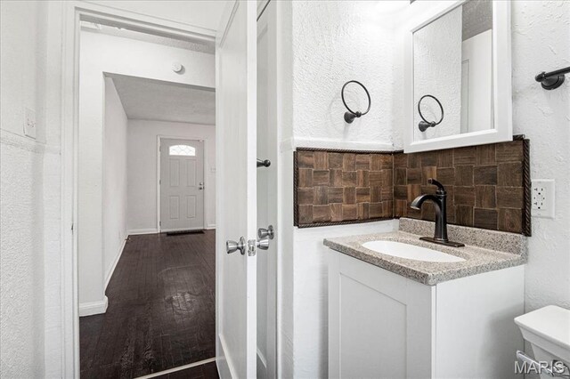 8505 Church Bell Ln, Jennings, MO 63136 - bathroom with vanity, tasteful backsplash, a textured wall, and wood finished floors