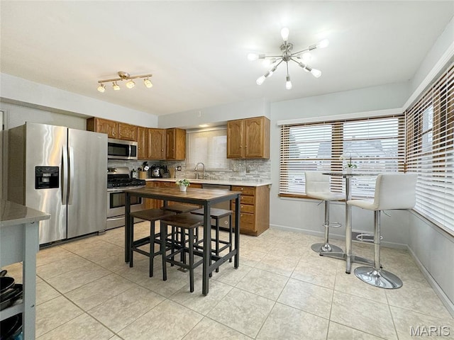 1001 Pike St, Saint Charles, MO 63301 - kitchen featuring stainless steel appliances, light tile patterned flooring, brown cabinetry, and a chandelier